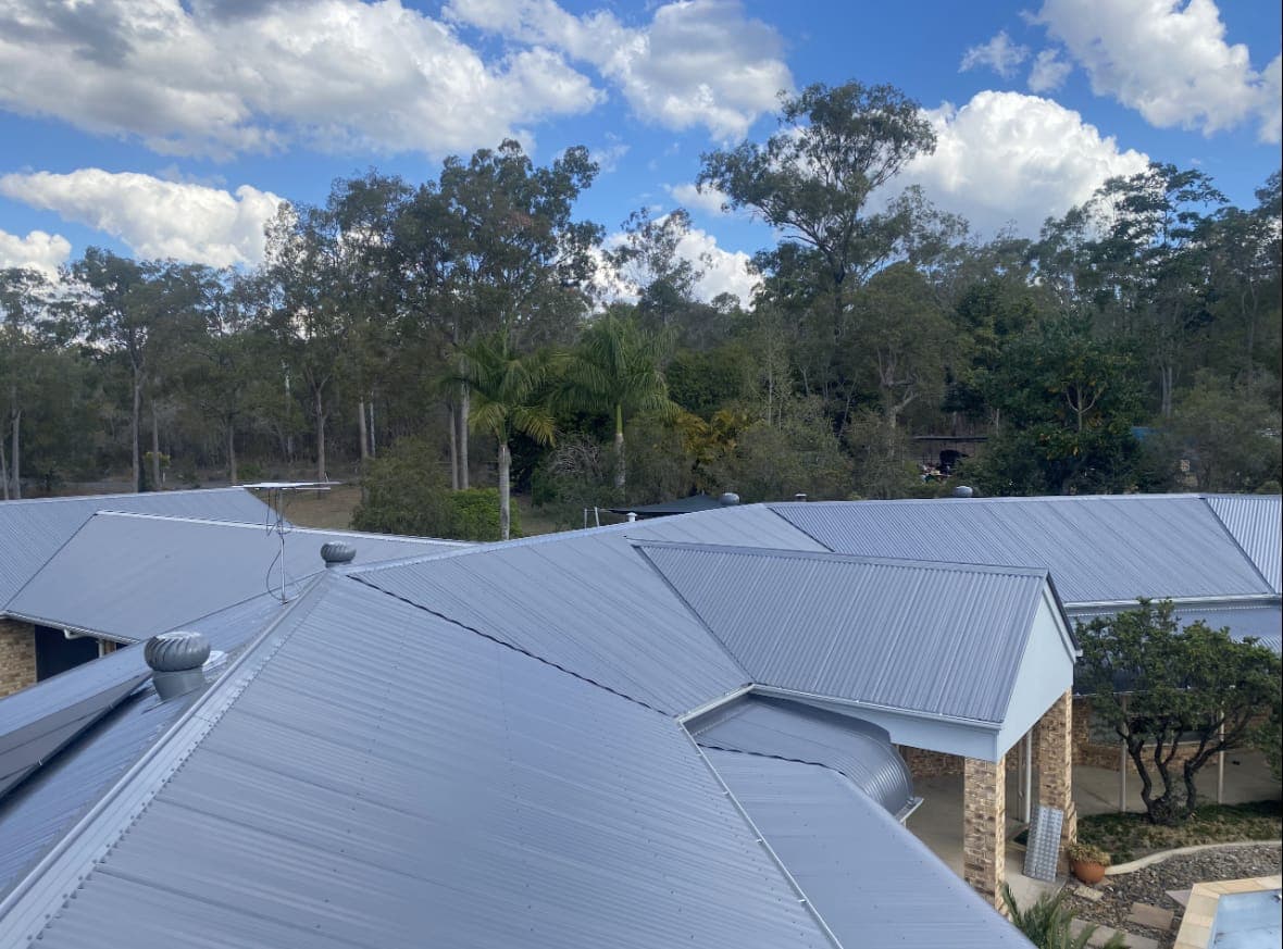Light grey Colorbond hip roof with multiple sections under a blue sky